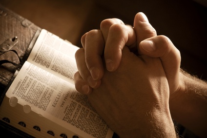 Praying Hands on an Open Bible